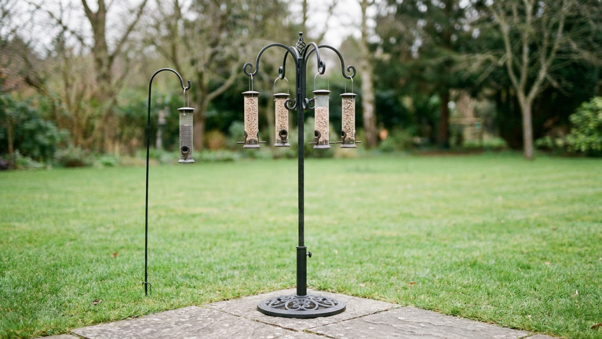 freestanding multi-arm bird feeder stand on a paver beside a single shepherd's hook on a lawn